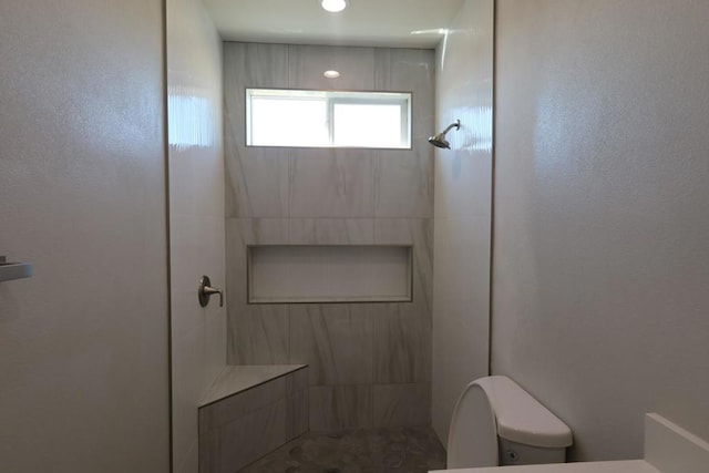 bathroom with toilet and a tile shower