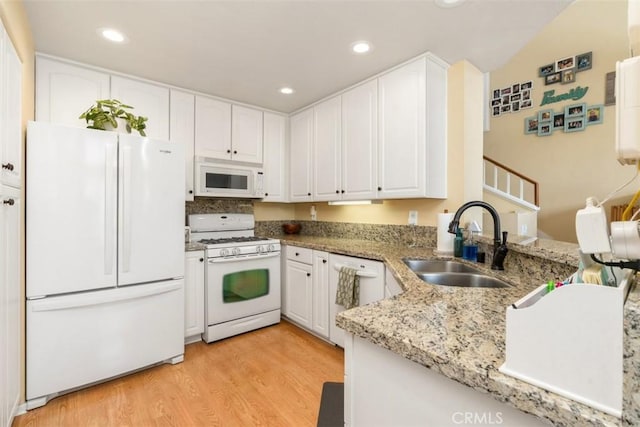 kitchen with sink, white cabinets, light stone counters, white appliances, and light hardwood / wood-style flooring