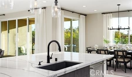 kitchen featuring decorative light fixtures, light stone countertops, and sink