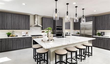 kitchen featuring sink, premium appliances, a kitchen island with sink, dark brown cabinets, and wall chimney exhaust hood