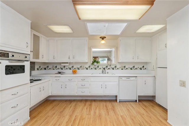 kitchen with white cabinetry, sink, white appliances, and light hardwood / wood-style floors