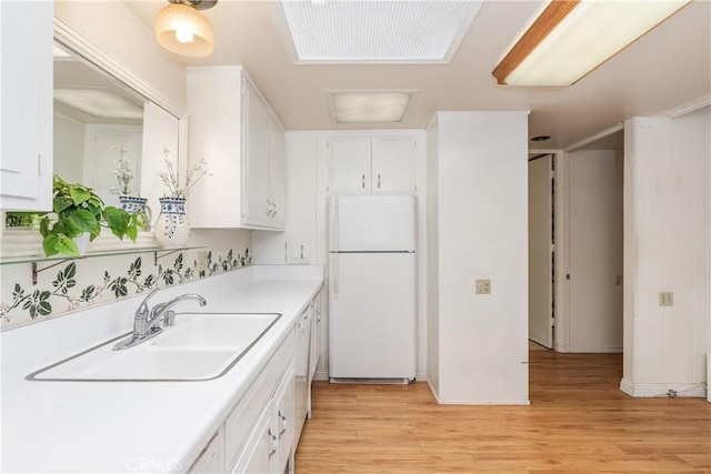 kitchen with sink, light hardwood / wood-style flooring, white cabinets, and white refrigerator