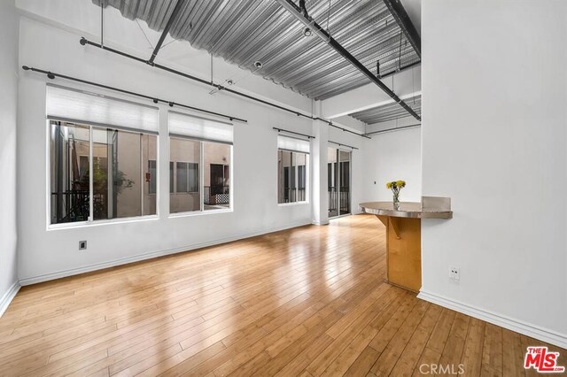 unfurnished living room featuring plenty of natural light and light hardwood / wood-style floors