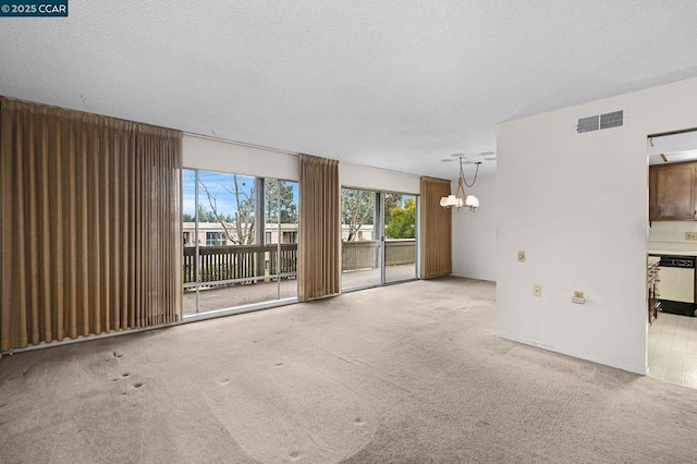 spare room with a notable chandelier, light carpet, and a textured ceiling