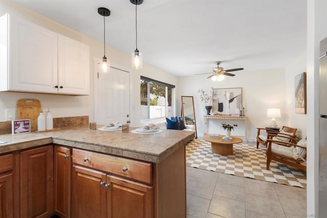 kitchen with light tile patterned flooring, hanging light fixtures, kitchen peninsula, ceiling fan, and white cabinets