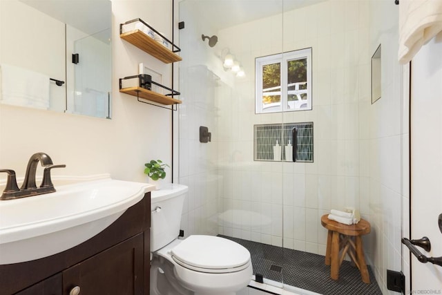 bathroom with a shower with door, vanity, and toilet