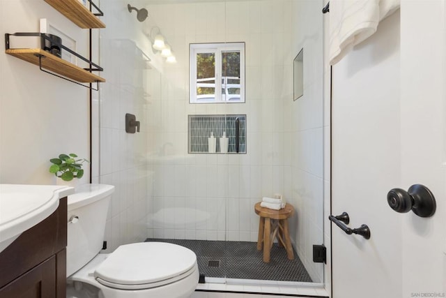 bathroom with vanity, a shower with door, and toilet