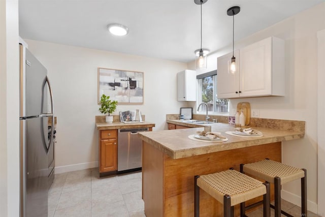 kitchen with sink, a breakfast bar, hanging light fixtures, stainless steel appliances, and kitchen peninsula