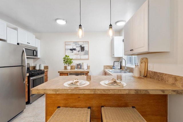 kitchen featuring sink, appliances with stainless steel finishes, white cabinetry, hanging light fixtures, and kitchen peninsula