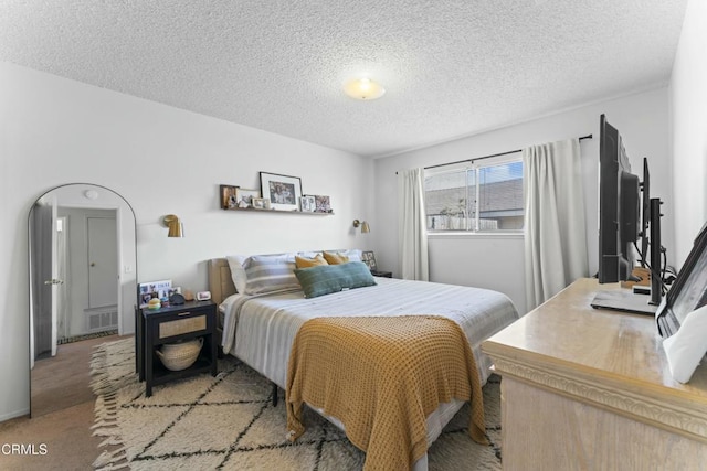 bedroom with visible vents, light carpet, and a textured ceiling