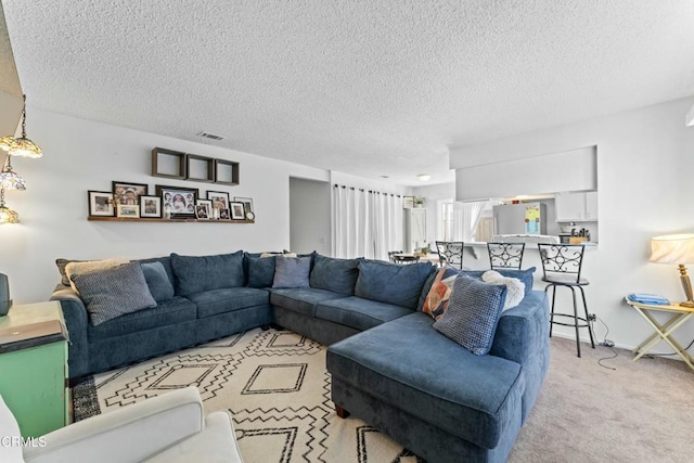 living area with visible vents, baseboards, light colored carpet, and a textured ceiling