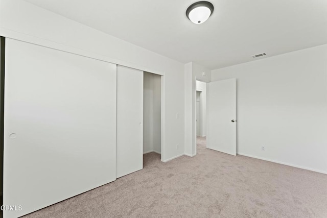 unfurnished bedroom with a closet, light colored carpet, baseboards, and visible vents