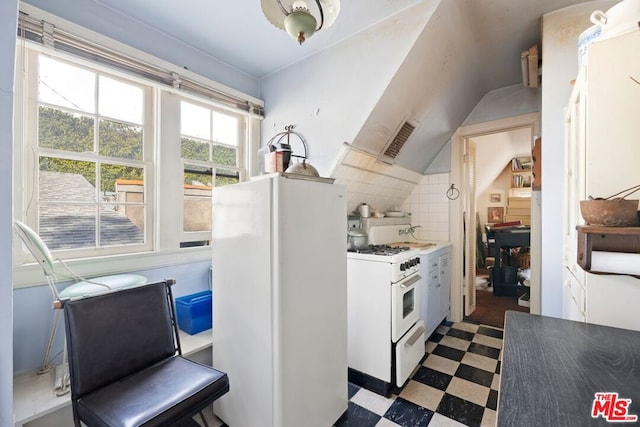 kitchen with white appliances, vaulted ceiling, and white cabinets