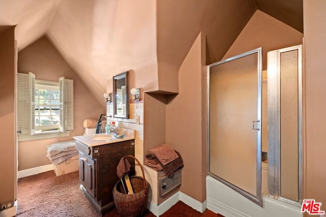 bathroom featuring vanity, combined bath / shower with glass door, and vaulted ceiling