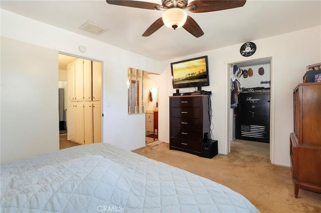 carpeted bedroom with connected bathroom, a walk in closet, and ceiling fan