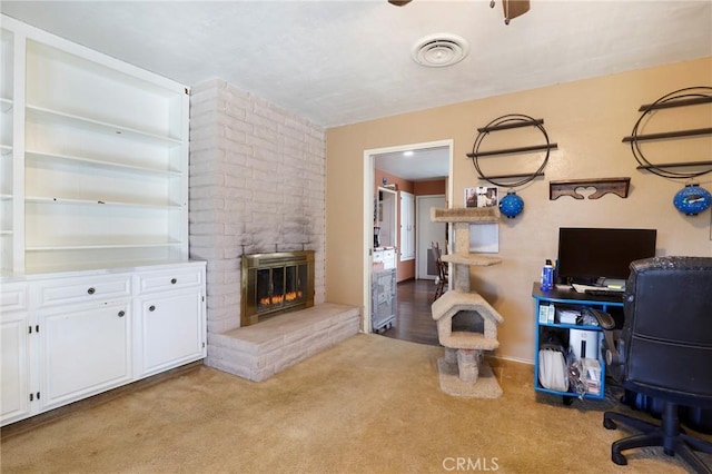 office space with a brick fireplace, light colored carpet, and ceiling fan