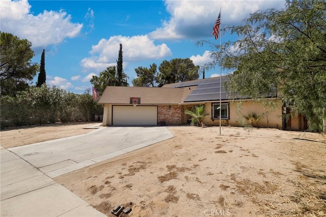 ranch-style house featuring a garage and solar panels