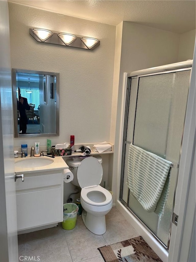 bathroom with a shower with shower door, vanity, toilet, tile patterned floors, and a textured ceiling