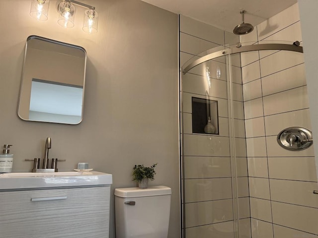 bathroom featuring vanity, toilet, and a tile shower