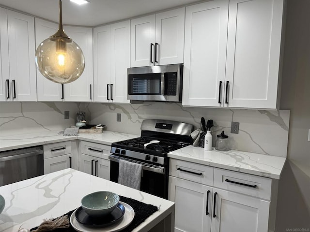 kitchen with white cabinetry, appliances with stainless steel finishes, hanging light fixtures, and backsplash