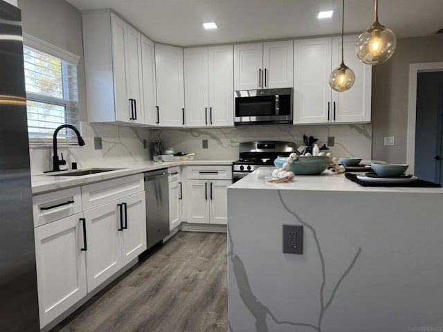 kitchen featuring hanging light fixtures, white cabinetry, appliances with stainless steel finishes, and sink