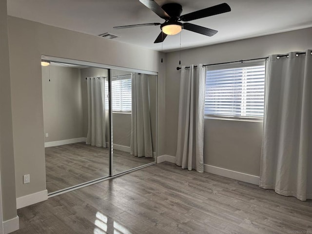 unfurnished bedroom featuring hardwood / wood-style flooring, a closet, and ceiling fan