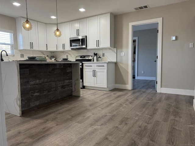 kitchen with hardwood / wood-style flooring, hanging light fixtures, backsplash, stainless steel appliances, and white cabinets