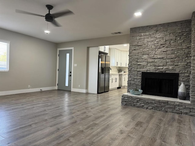 unfurnished living room with ceiling fan, a fireplace, and light hardwood / wood-style floors