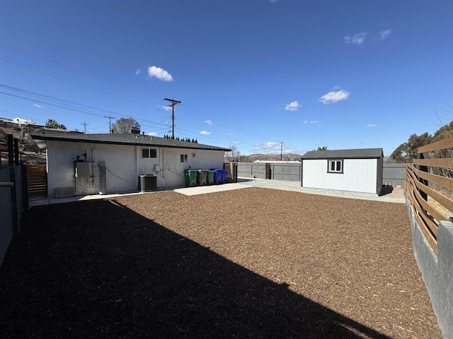 rear view of property with cooling unit and a shed