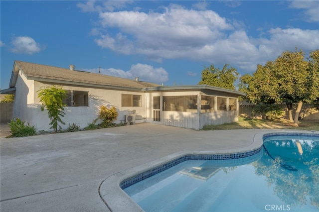 back of property featuring an outdoor pool, a patio, a sunroom, fence, and stucco siding