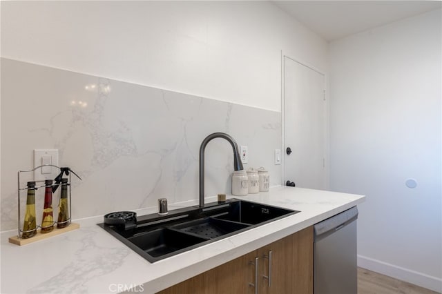 kitchen featuring dishwasher, light countertops, brown cabinetry, and a sink