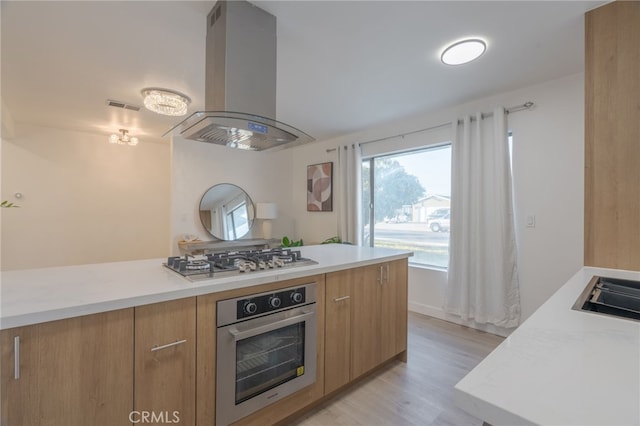 kitchen with modern cabinets, island range hood, stainless steel appliances, and light countertops