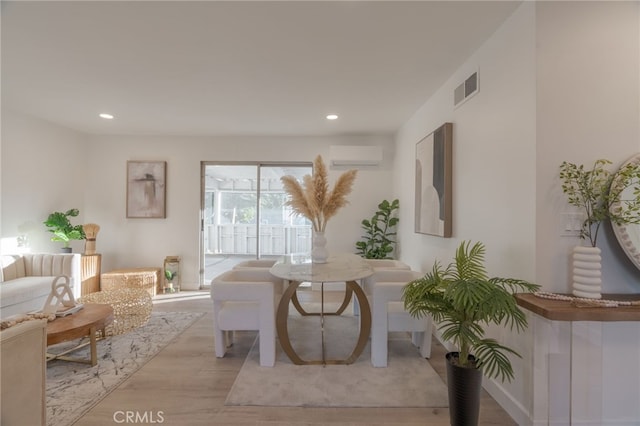 sitting room with recessed lighting, an AC wall unit, visible vents, and light wood finished floors