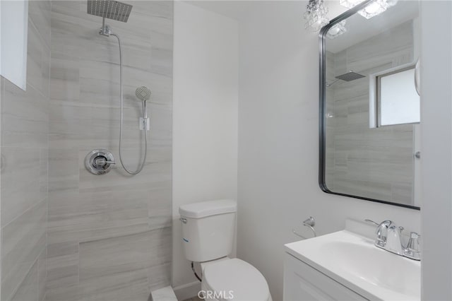 bathroom with toilet, tiled shower, and vanity