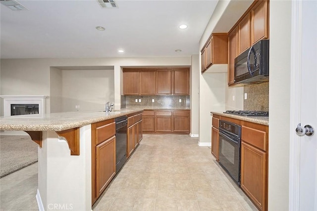 kitchen featuring sink, backsplash, a kitchen breakfast bar, black appliances, and kitchen peninsula