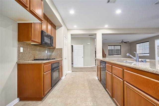 kitchen featuring sink, decorative backsplash, ceiling fan, black appliances, and light stone countertops