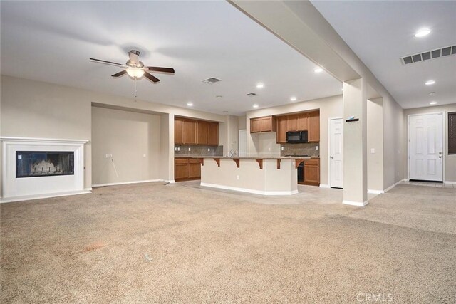 unfurnished living room featuring ceiling fan and light colored carpet