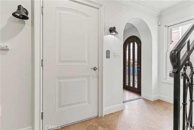 entrance foyer featuring crown molding and light tile patterned floors