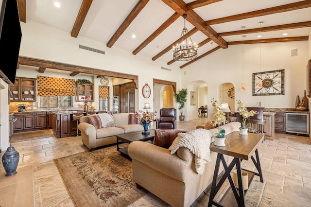 living room with wine cooler, beam ceiling, high vaulted ceiling, and a notable chandelier