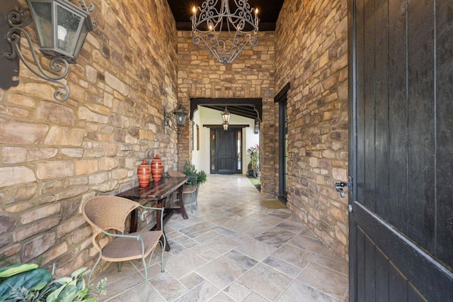 hallway featuring an inviting chandelier and a high ceiling