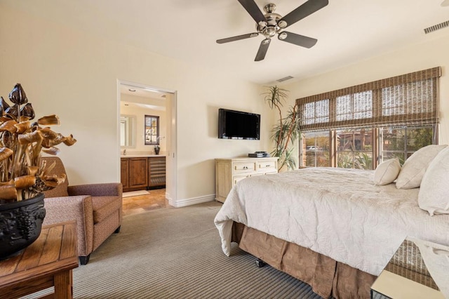 bedroom featuring connected bathroom, light colored carpet, and ceiling fan