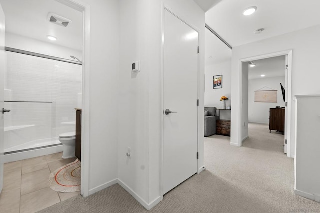 bathroom featuring tile patterned flooring, toilet, and walk in shower