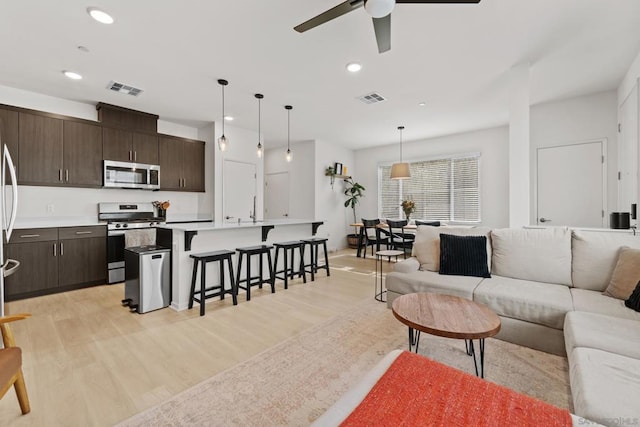 living room with ceiling fan and light hardwood / wood-style flooring