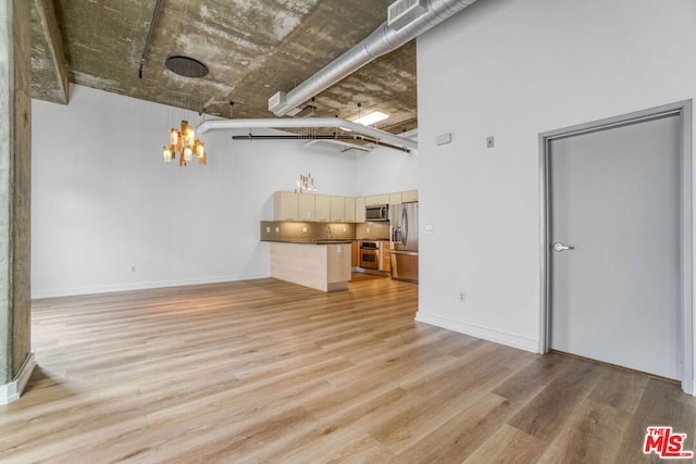 unfurnished living room featuring a chandelier, light hardwood / wood-style floors, and a high ceiling