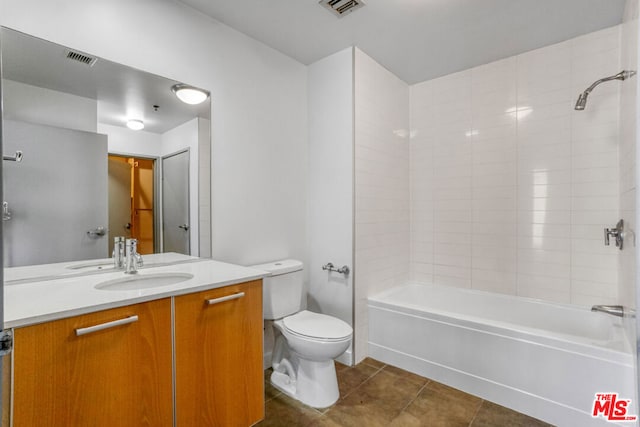 full bathroom featuring tile patterned flooring, tiled shower / bath, vanity, and toilet