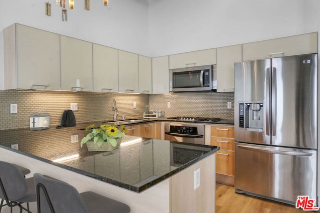 kitchen featuring appliances with stainless steel finishes, sink, a breakfast bar area, and dark stone counters