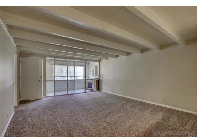 unfurnished room with beamed ceiling and carpet