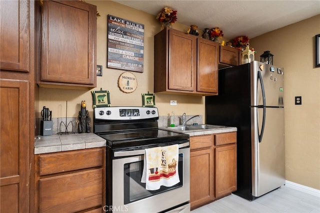 kitchen with appliances with stainless steel finishes, sink, and tile counters