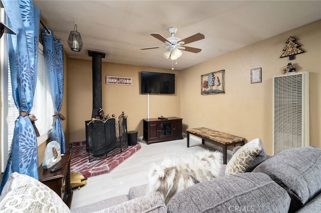 living room with a wood stove and ceiling fan