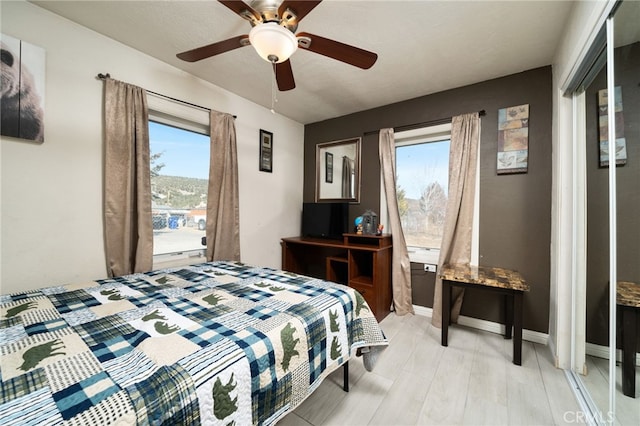 bedroom with multiple windows, wood-type flooring, and ceiling fan